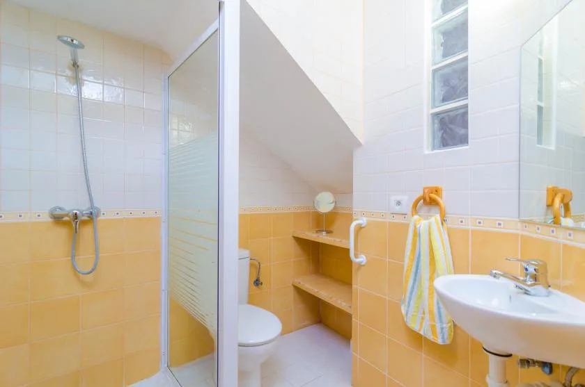 A tiled bathroom with a shower, sink, and towel hanging nearby.