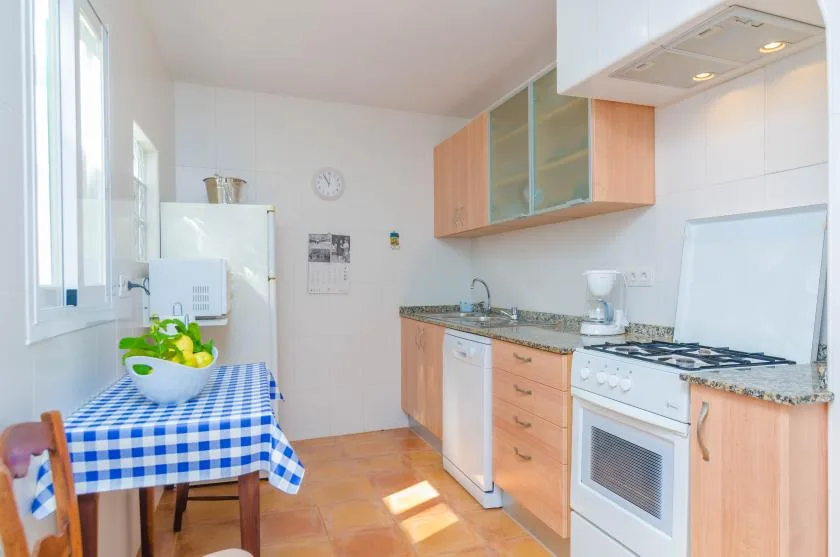 A bright kitchen with a checkered tablecloth and wooden cabinets.