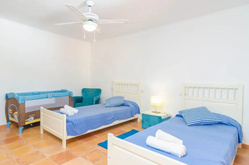 A bright bedroom with two beds and a crib.