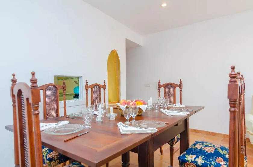 A dining room with a wooden table set with dishes and glassware.