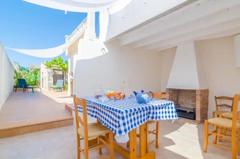 An outdoor dining patio with a checkered tablecloth and seating under a white canopy.