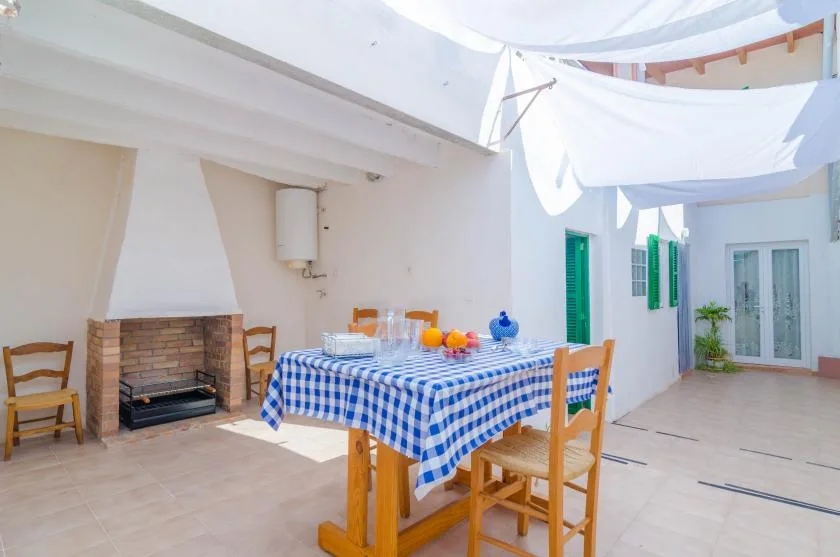 A tiled patio dining area with a blue-checkered table beneath white shade fabric.