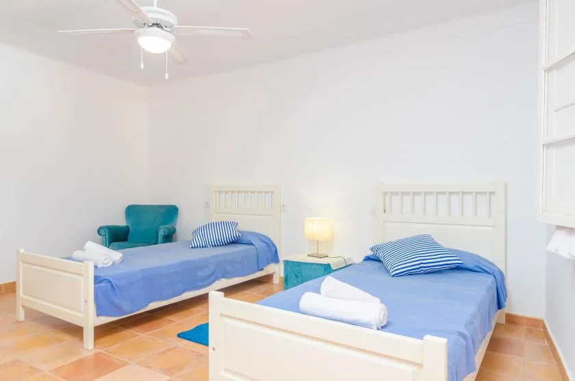 A bedroom with two beds dressed in blue bedding and striped pillows.
