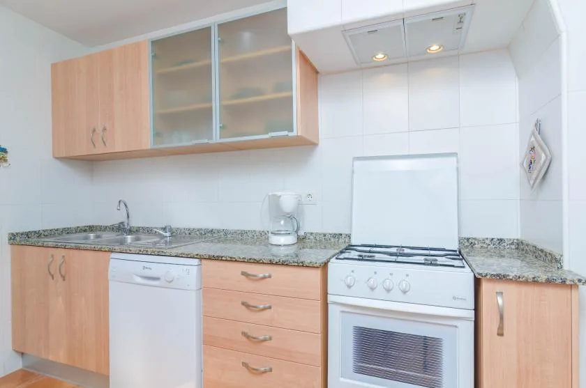 A bright kitchen with wood cabinets, a countertop, and a freestanding stove.