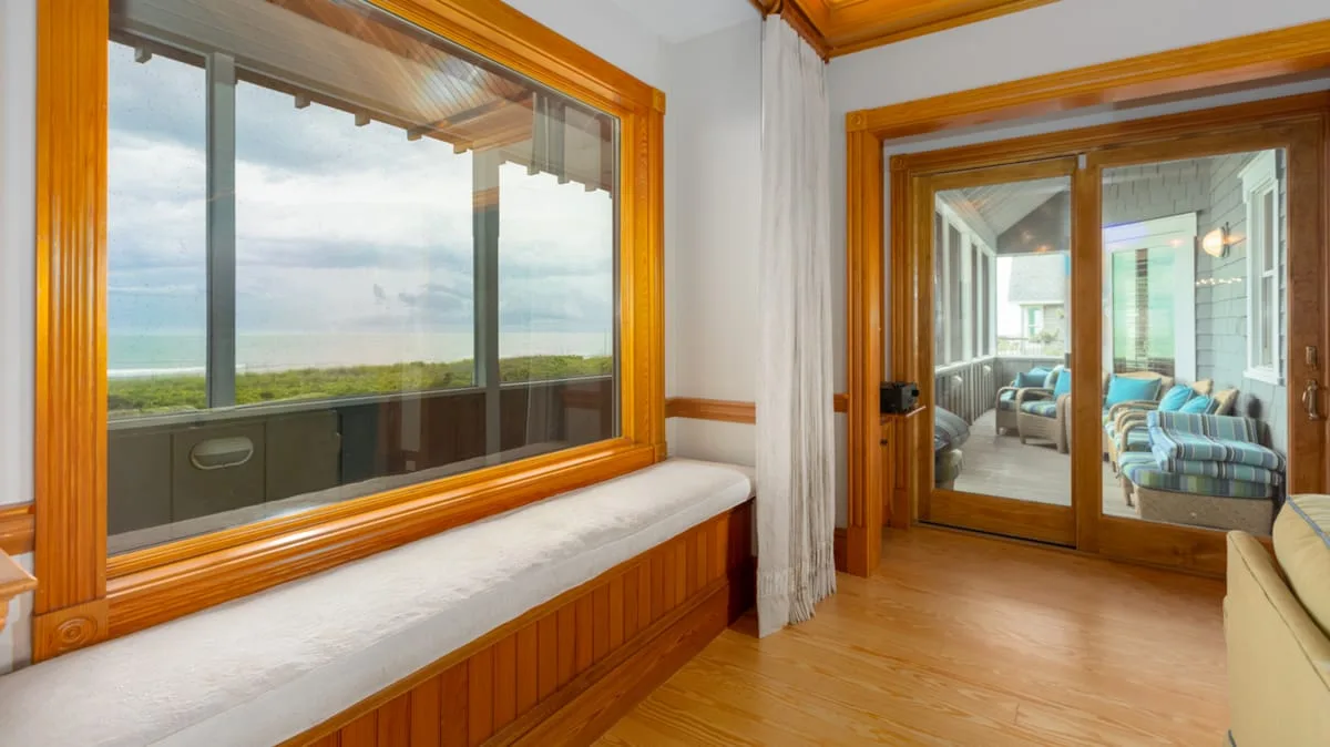 Una luminosa zona de estar con un asiento junto a la ventana y vistas a un paisaje verde.