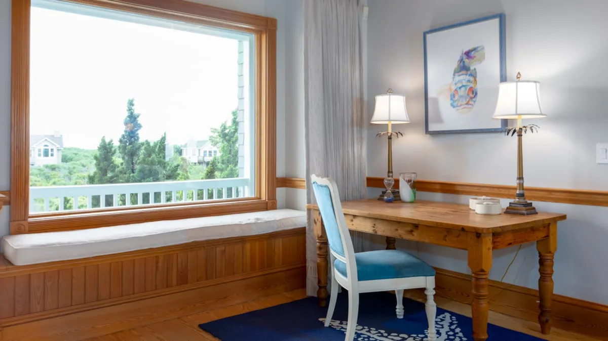 Un escritorio de madera y asientos azules están junto a una ventana grande.