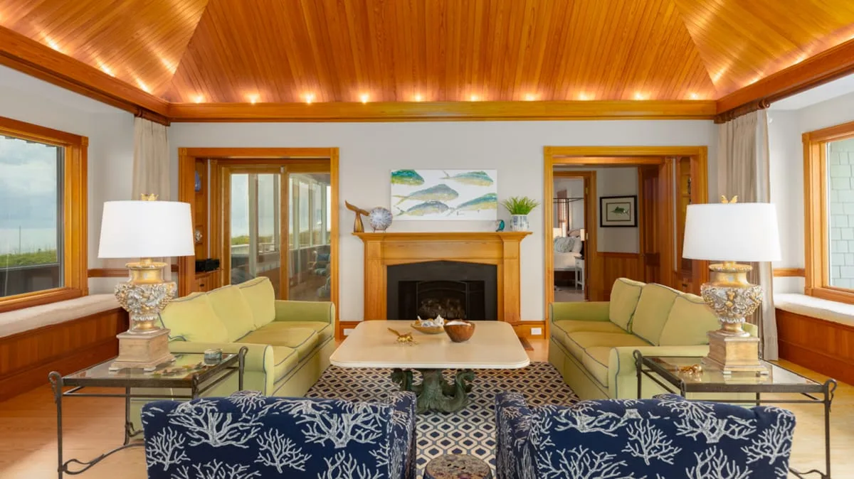 Sala de estar con asientos alrededor de una chimenea y una mesa central.