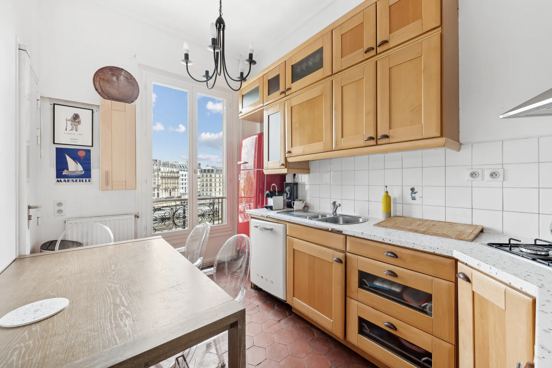 A bright kitchen with wooden cabinets, a dining table, and tall windows.