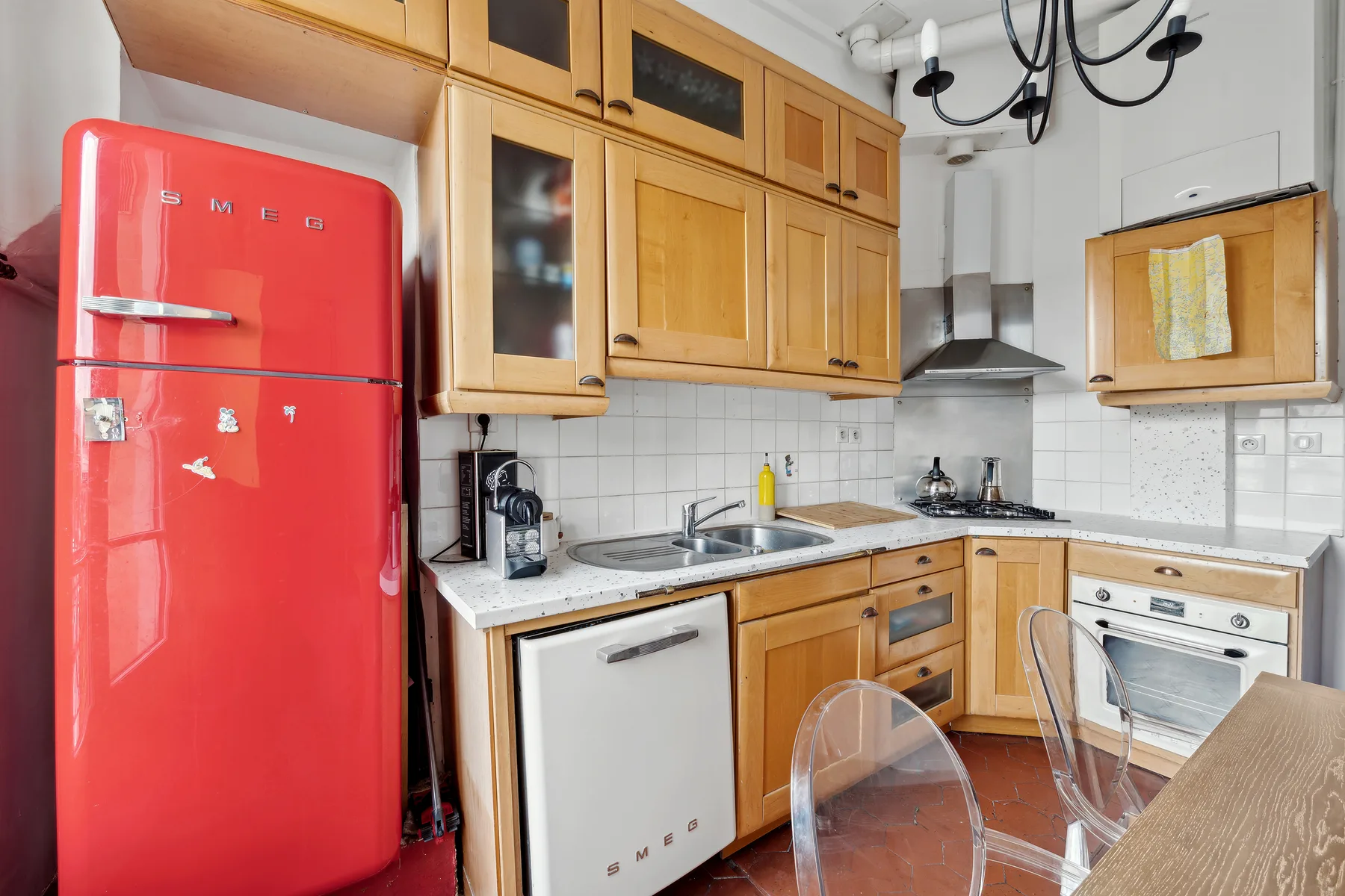 A compact kitchen with wooden cabinets, a red refrigerator, and a countertop.