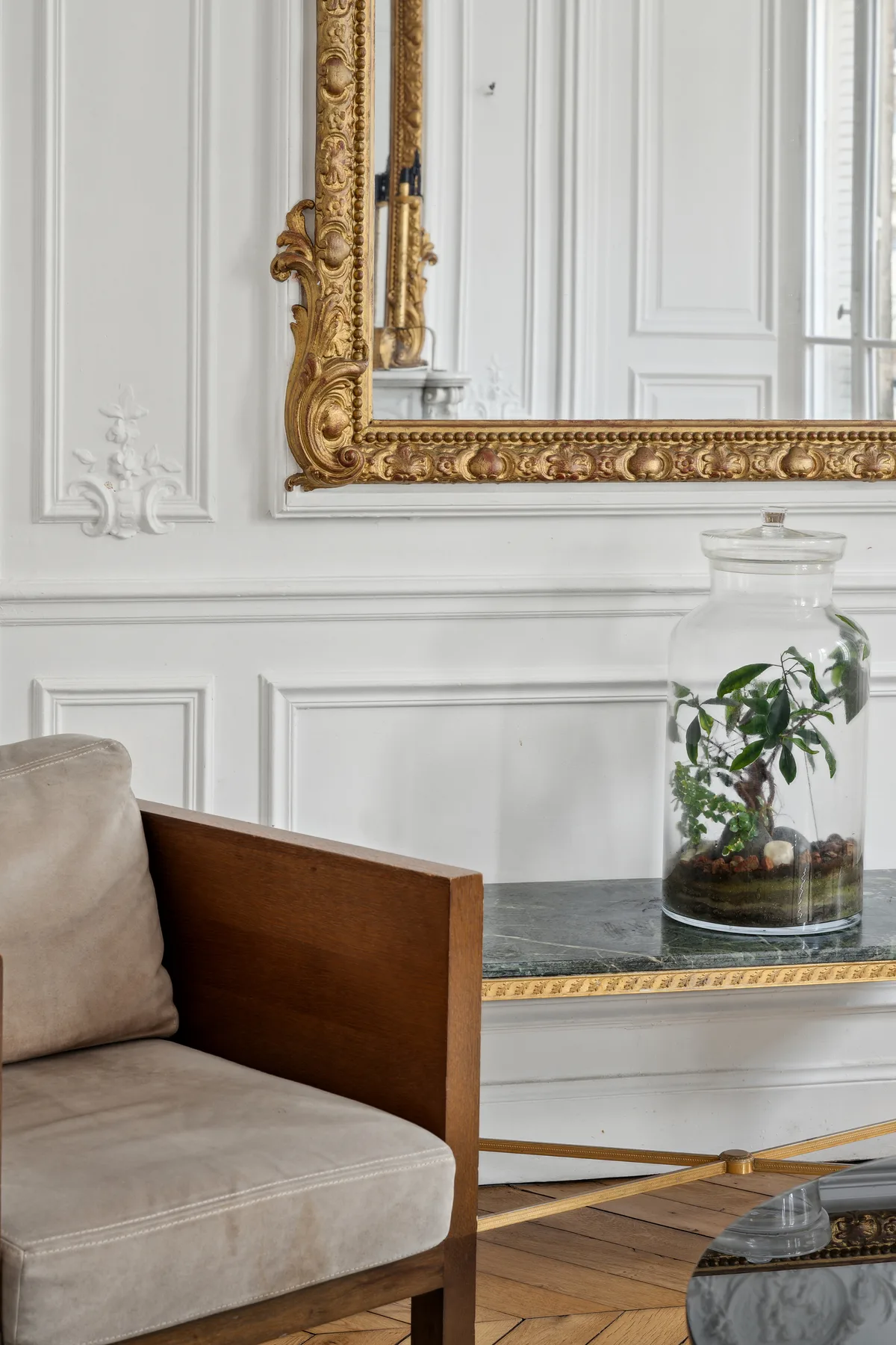 Una sala luminosa con asientos tapizados y un espejo con marco dorado ornamentado.