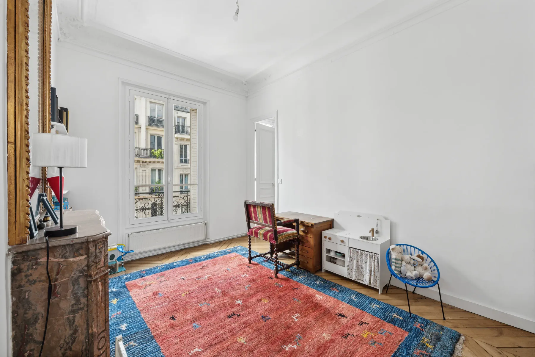 A bright living room with a colorful rug and seating by the window.
