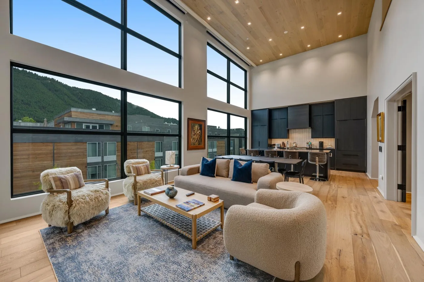 A spacious living room with seating, a coffee table, and large windows.