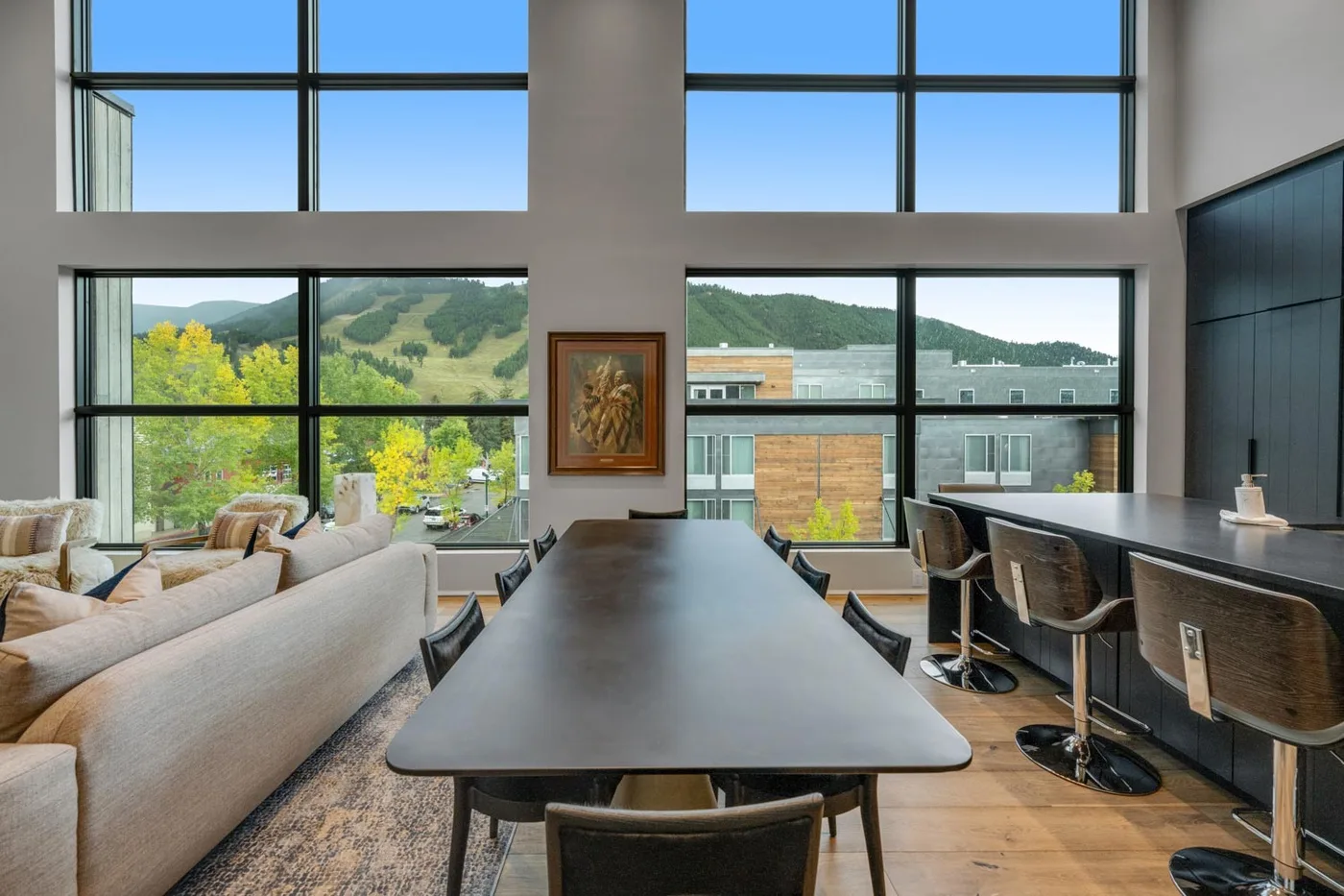 A spacious dining area with a long table and large windows overlooking green hills.