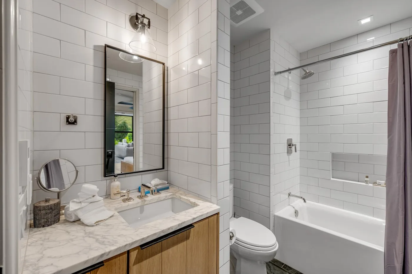 A tiled bathroom with a sink vanity, toilet, and bathtub.