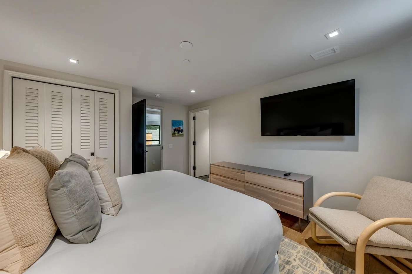 A bedroom with a bed, a wall-mounted television, and a seating area.