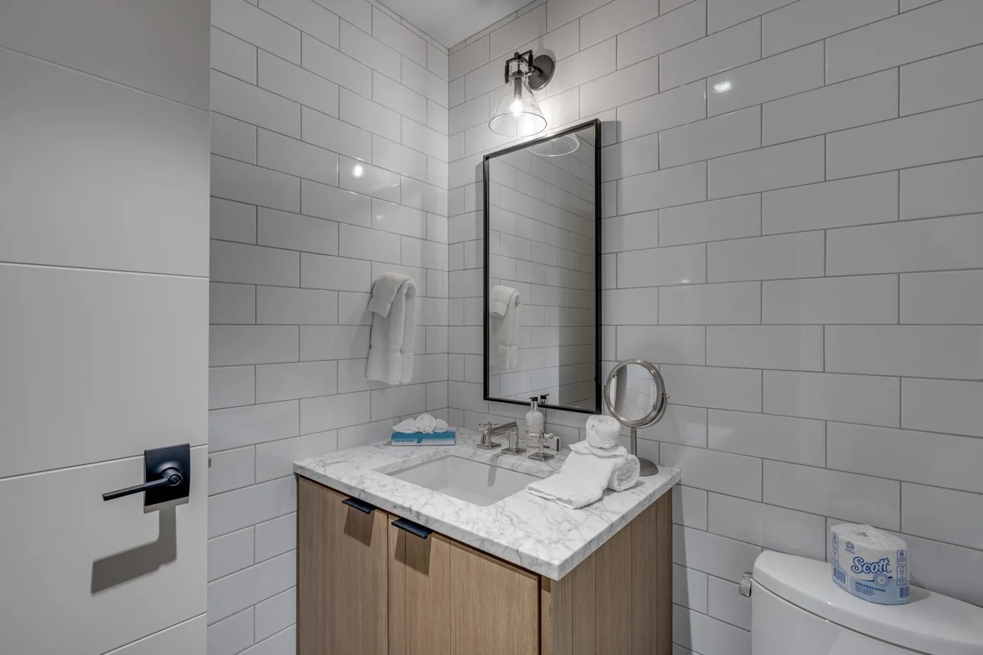 A tiled bathroom with a sink vanity, mirror, and toilet.