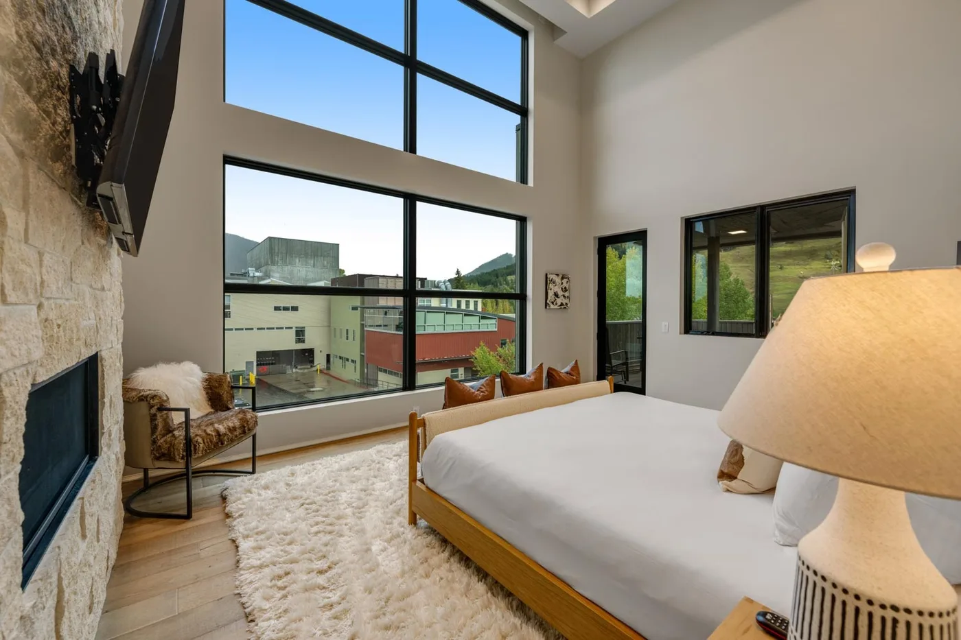 A bedroom with a bed, a tall window, and a sitting area.