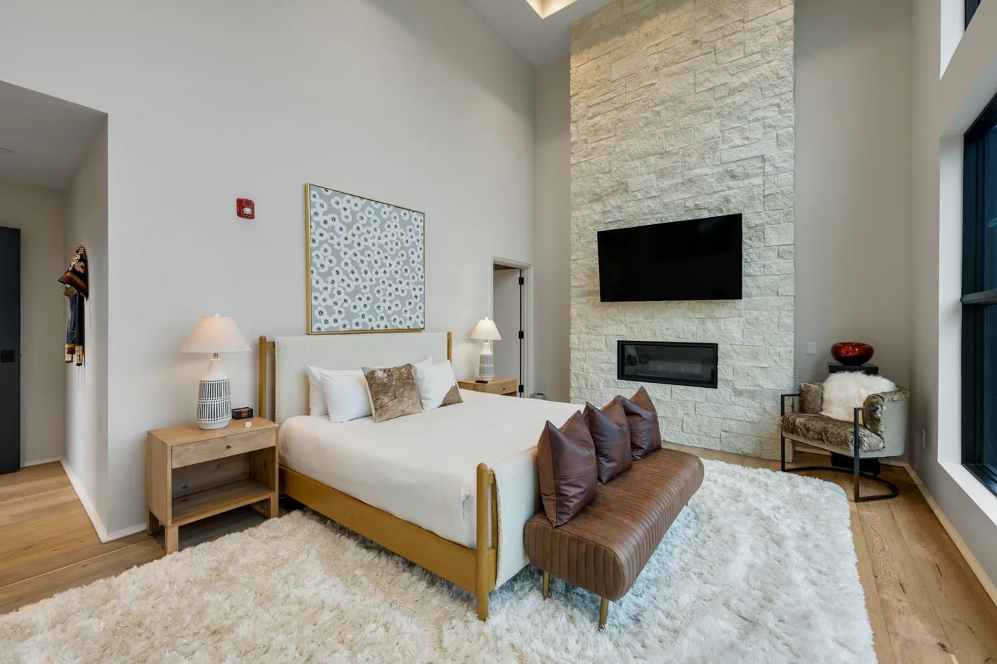 A bedroom with a bed, a television, and a stone accent wall.