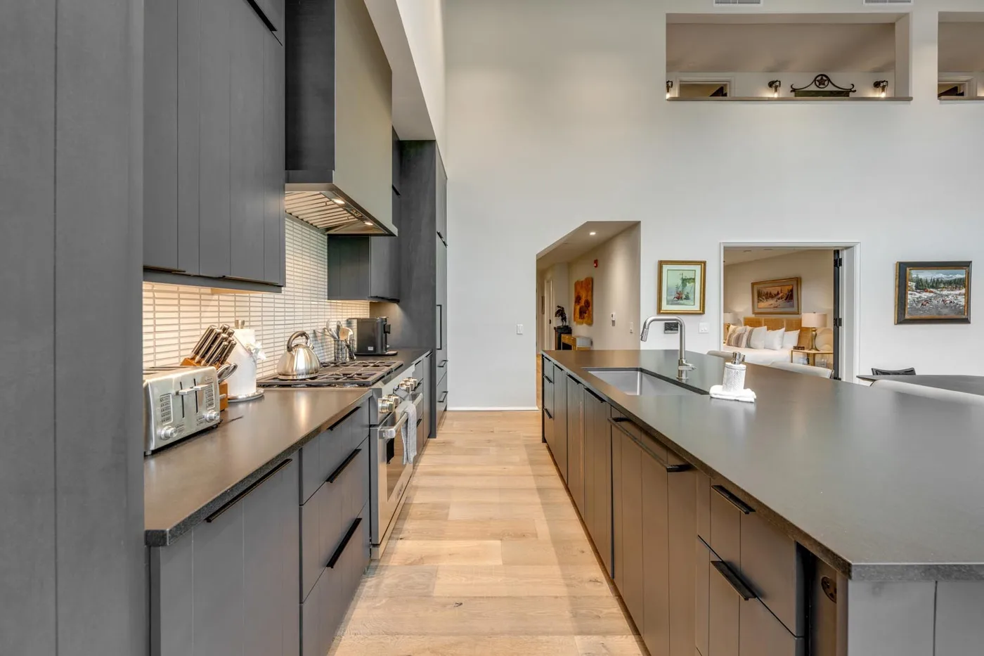 A modern kitchen with a long island and dark cabinetry.