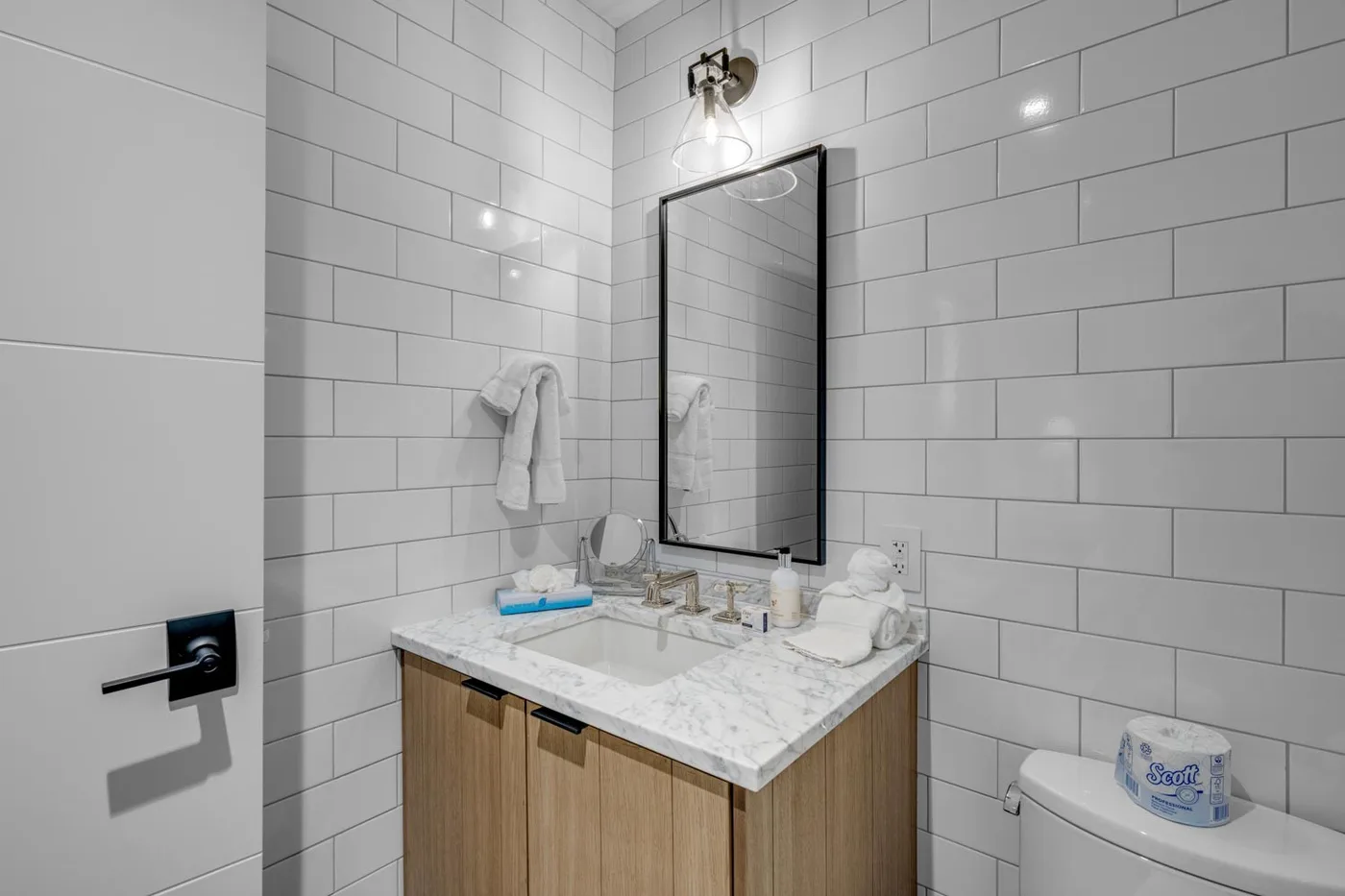 A tiled bathroom vanity with a mirror, sink, and wooden cabinet.