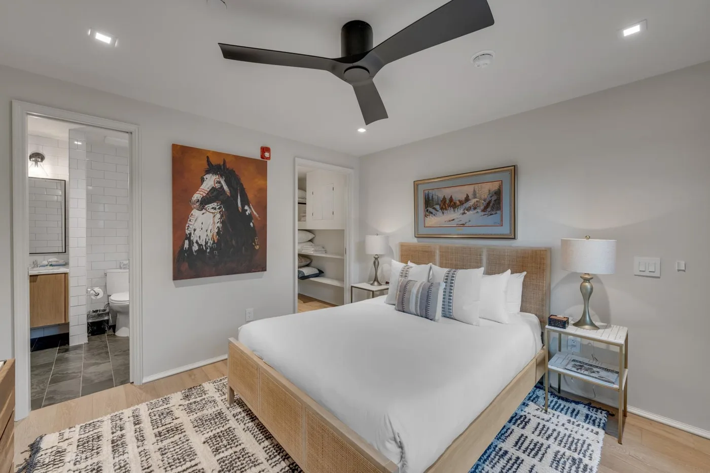 A bright bedroom with a neatly made bed and framed artwork.