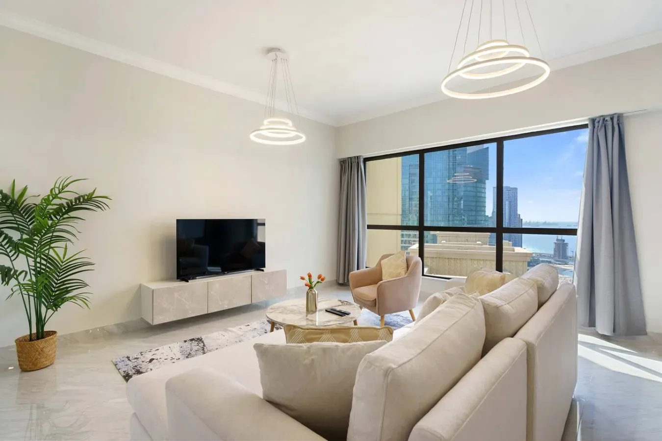 Una sala luminosa con una zona de estar junto a grandes ventanas.