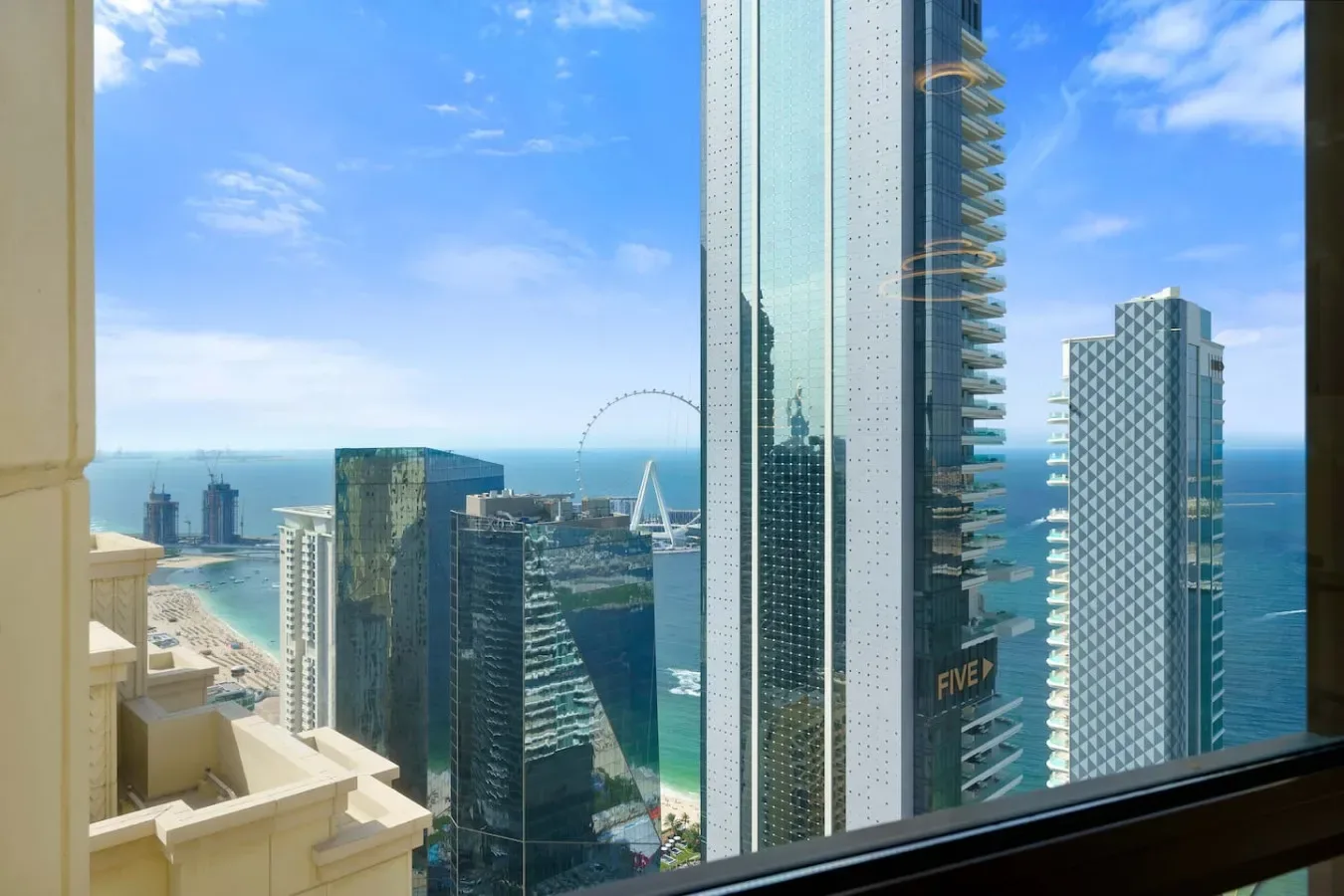 Vista de la ciudad y el océano a través de una ventana en un día soleado.