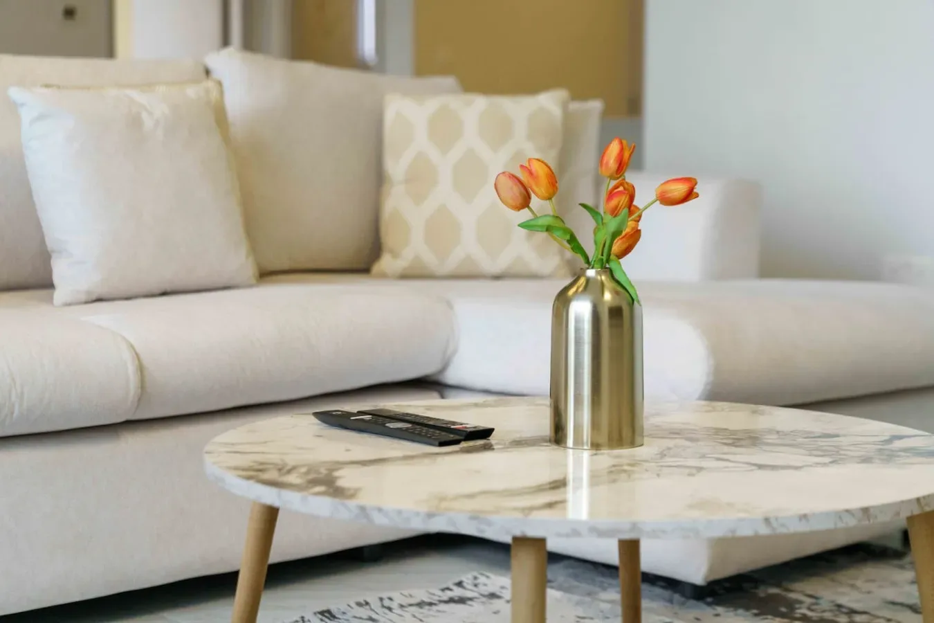A living room seating area with a round coffee table and flowers.