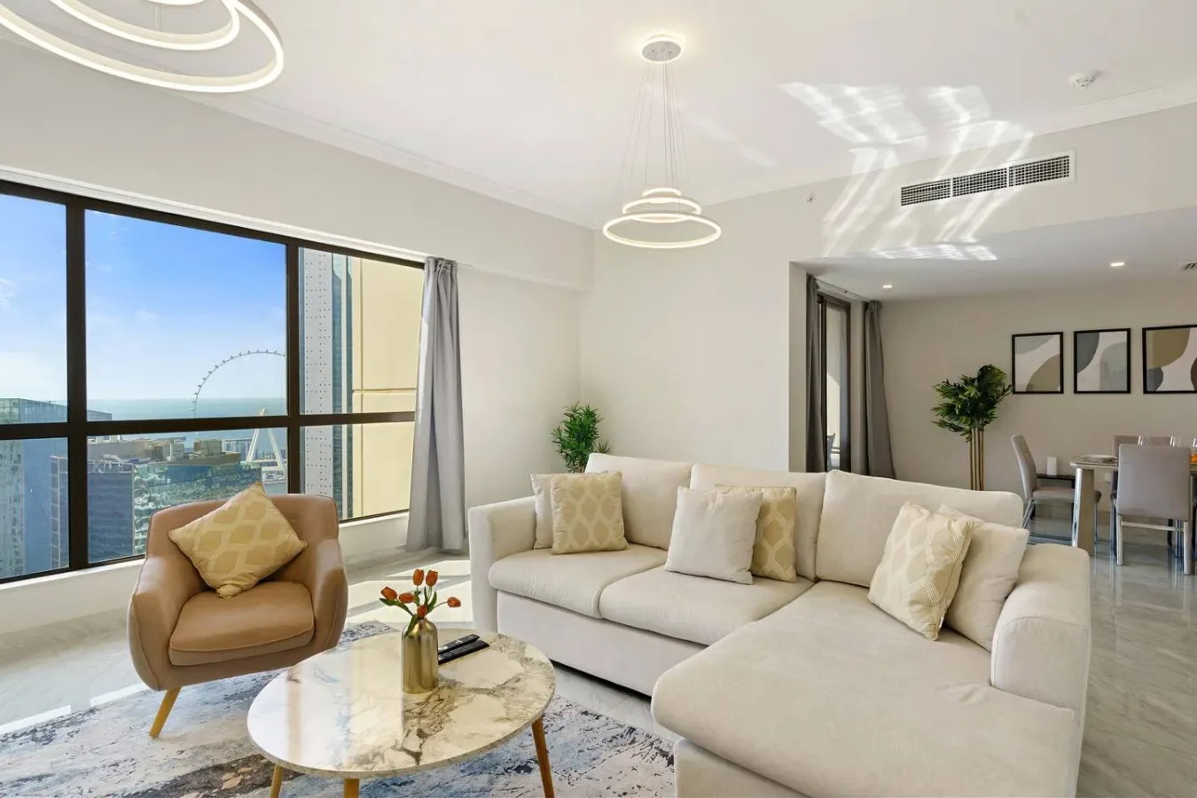 A bright living room with a sectional seating area beside floor-to-ceiling windows.