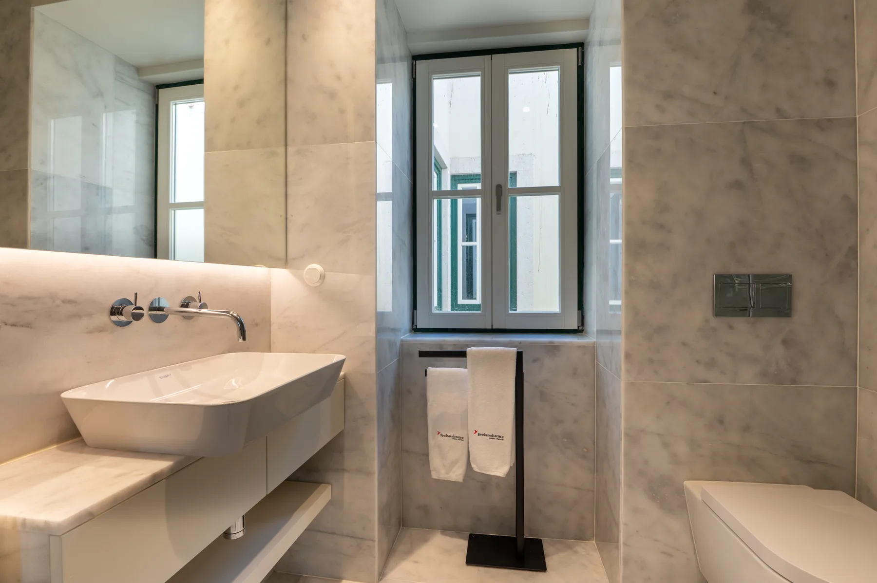 Un baño con azulejos, un lavabo suspendido y una ventana.