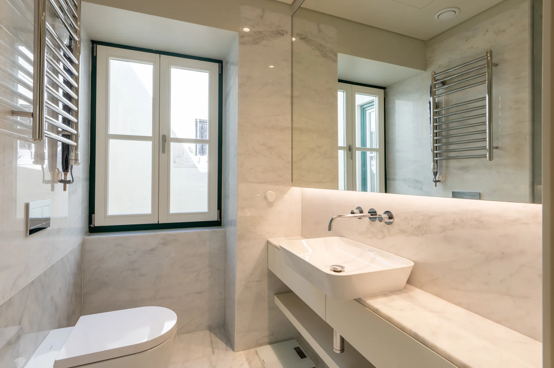 Un baño luminoso con lavabo, inodoro y un espejo grande.