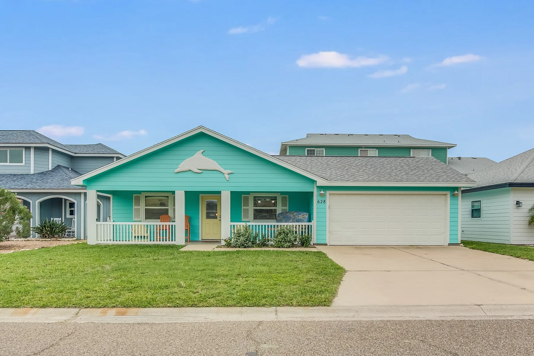A turquoise single-story house with a white garage door and lawn.