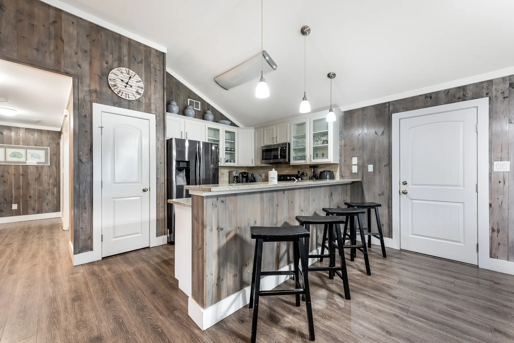 A kitchen with a counter, stools, and white cabinets.
