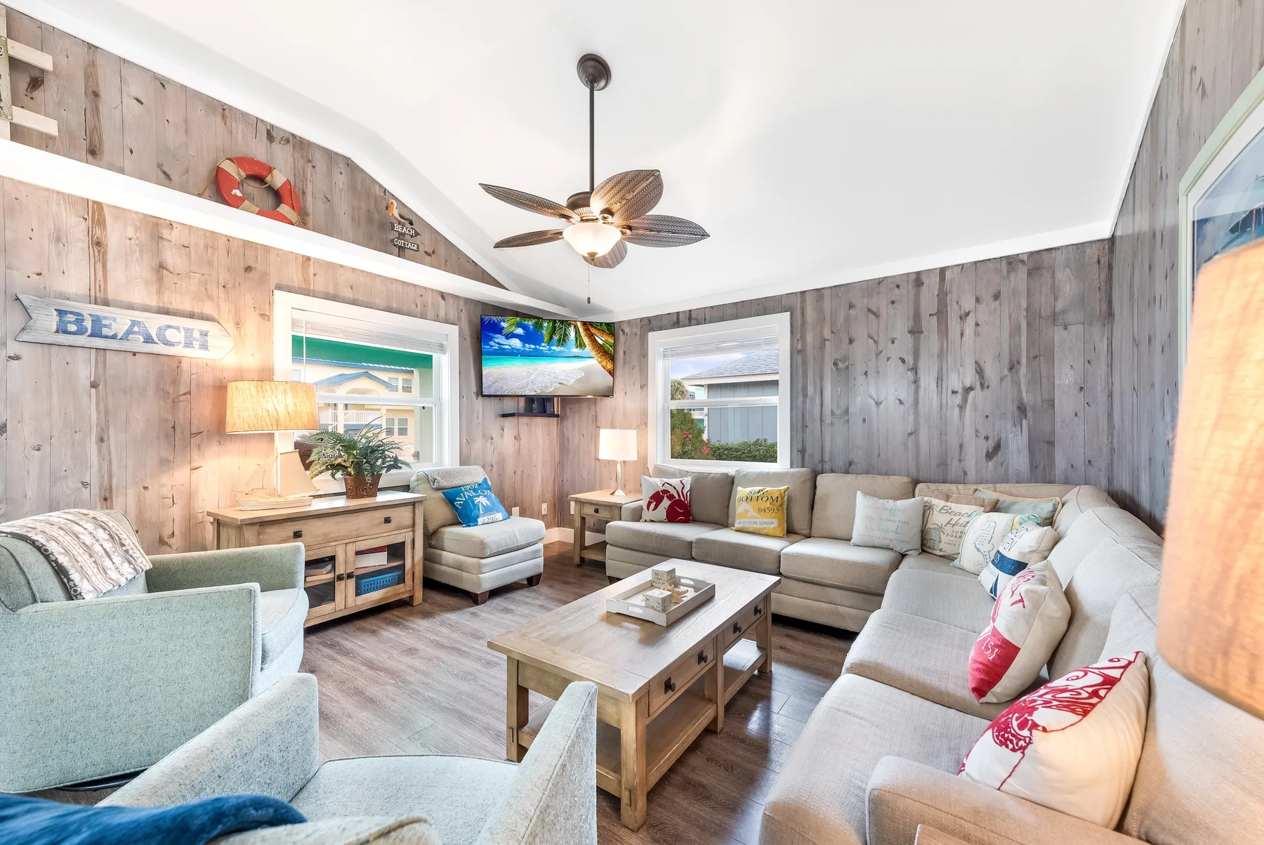 A living room with sectional seating, a coffee table, and wood-paneled walls.