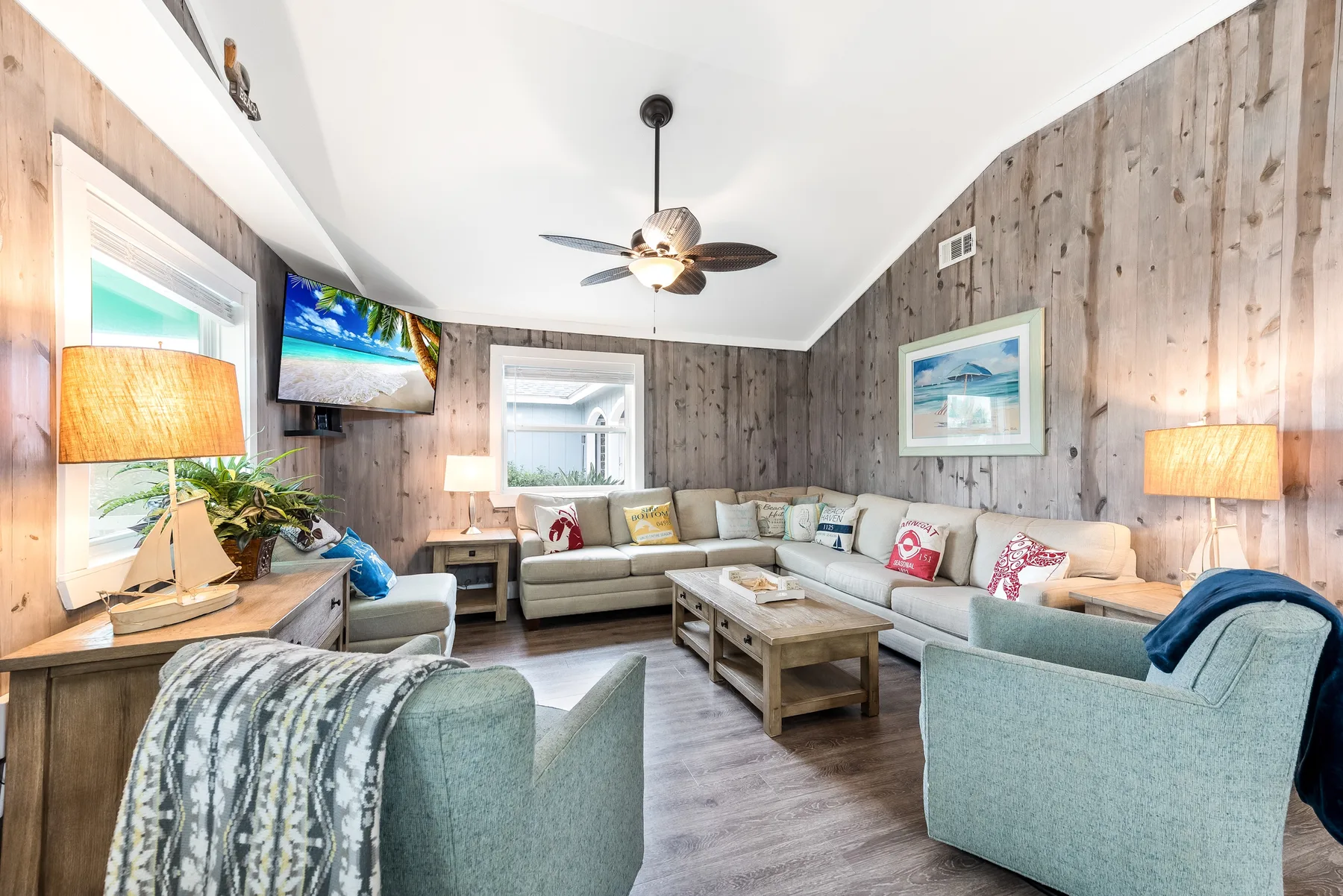A living room with a sectional seating area, coffee table, and ceiling fan.