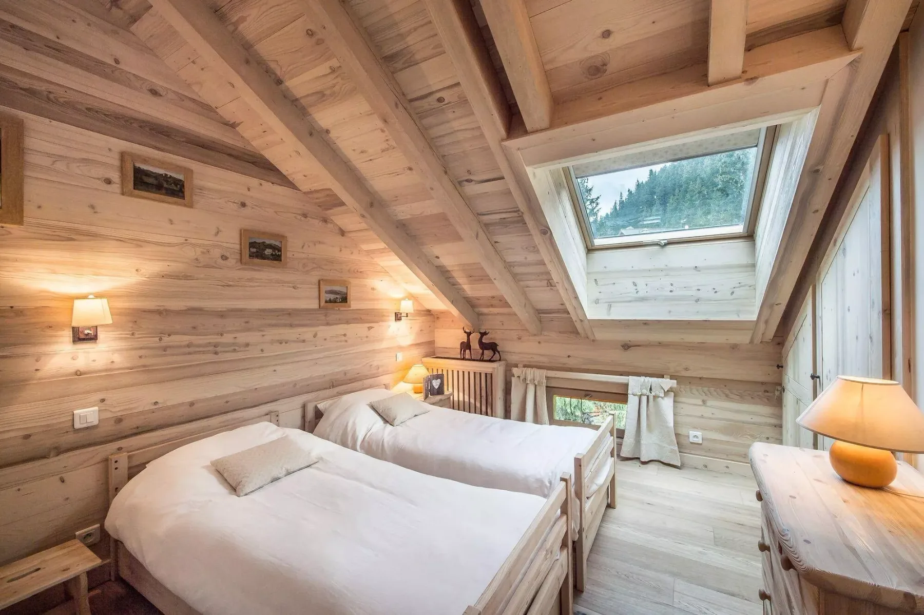 Un dormitorio revestido de madera con dos camas y un gran tragaluz.