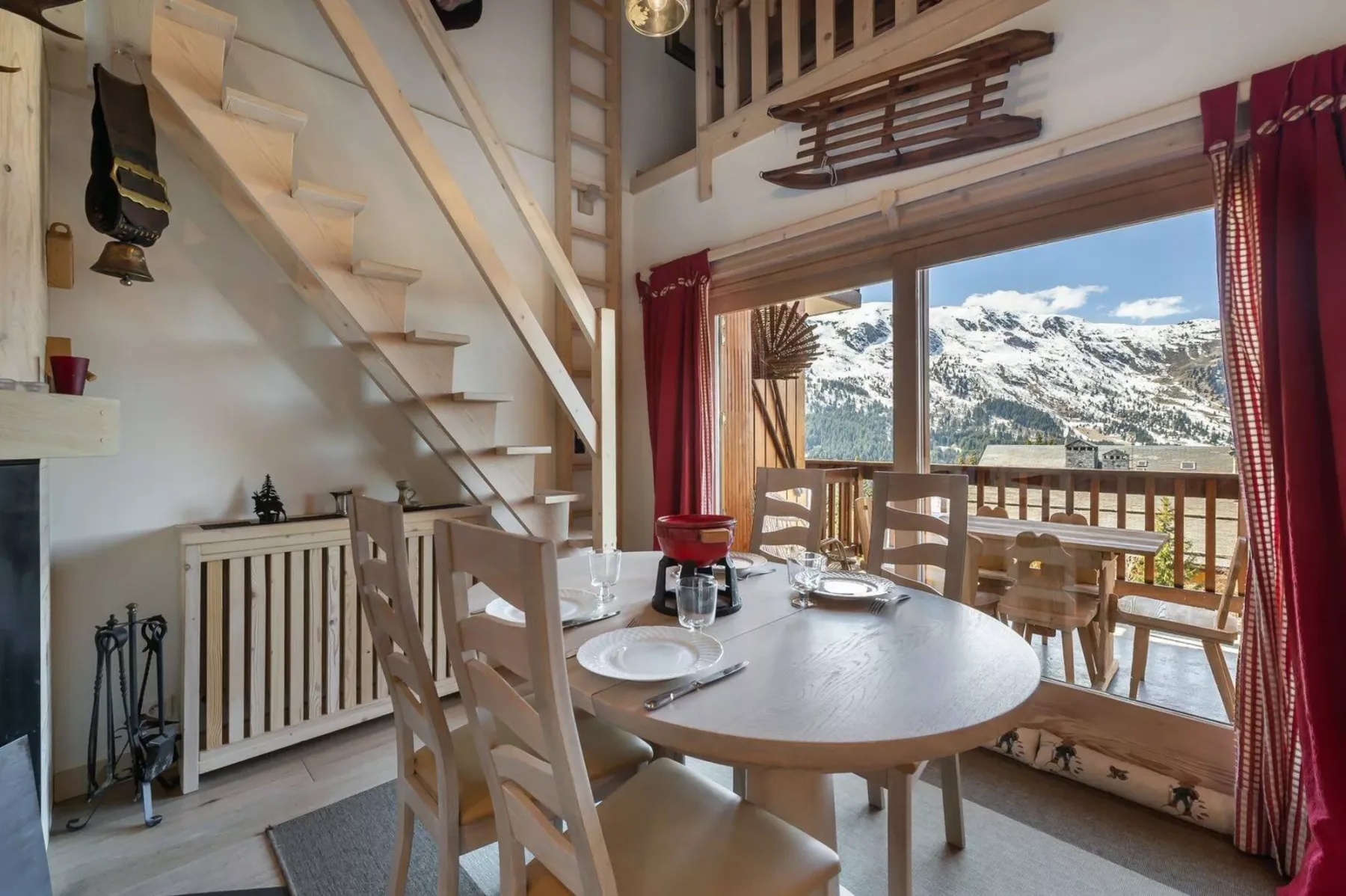 A dining area with a table and chairs beside windows overlooking snowy mountains.