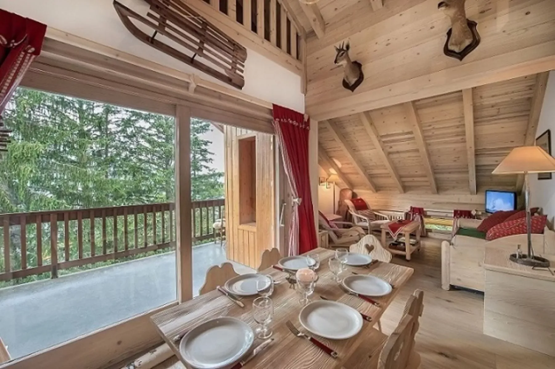 Una zona de comedor y estar revestida de madera da a un balcón a través de grandes puertas de vidrio.