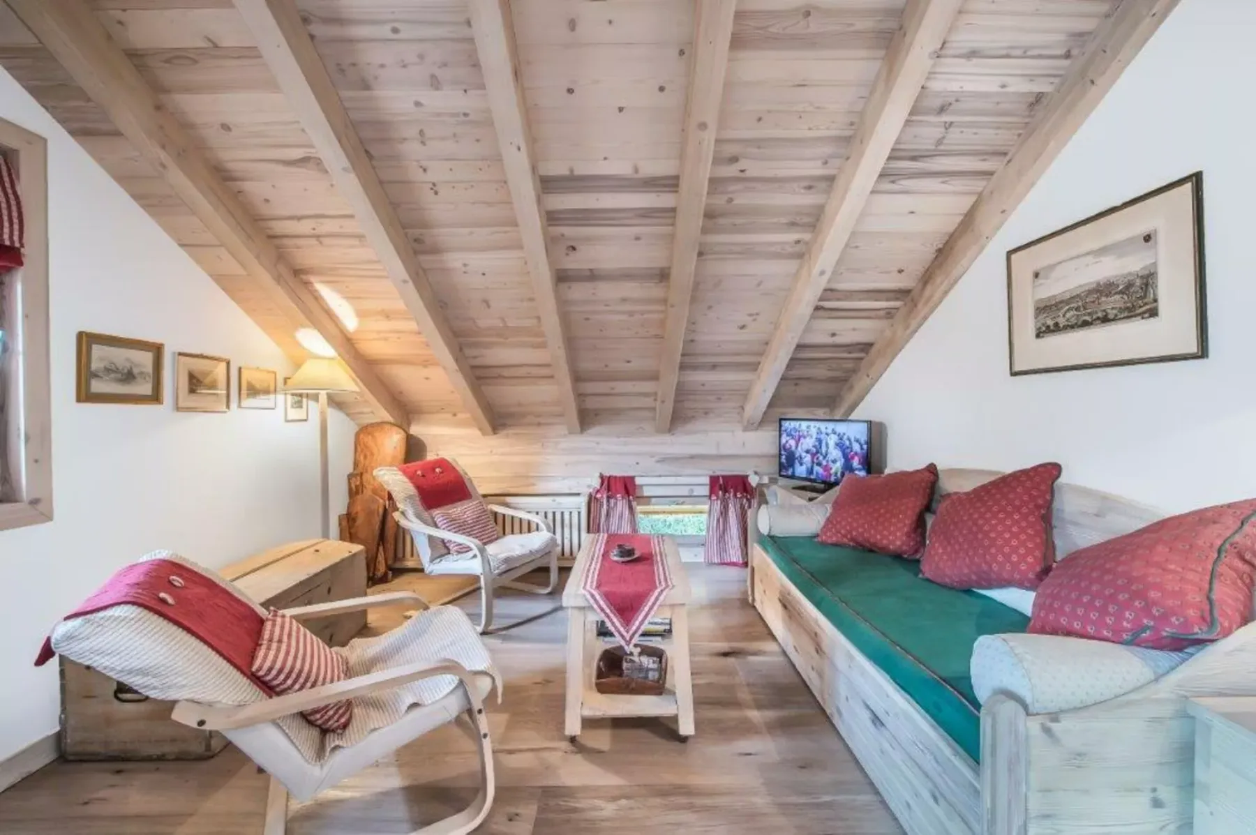 A cozy loft sitting area with seating beneath a sloped wooden ceiling.
