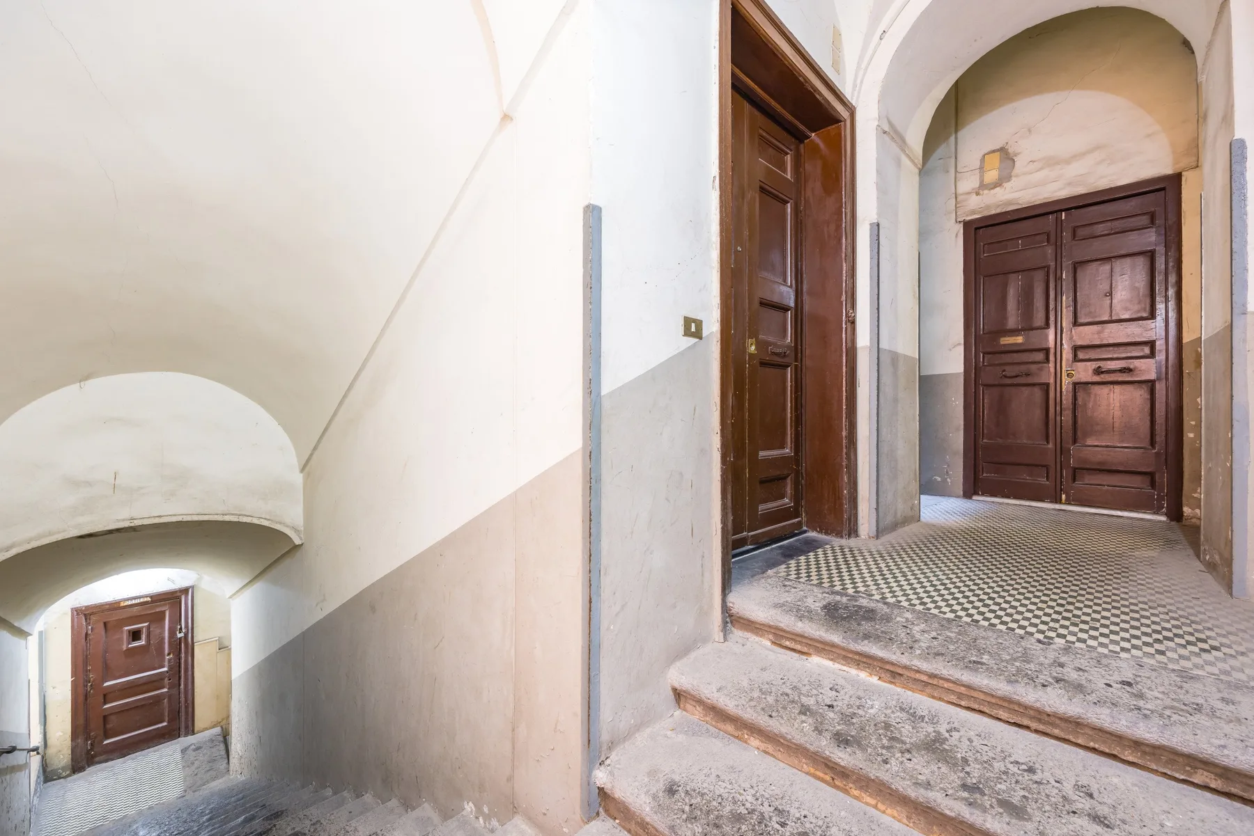 An interior entryway with dark wooden doors and stone steps.