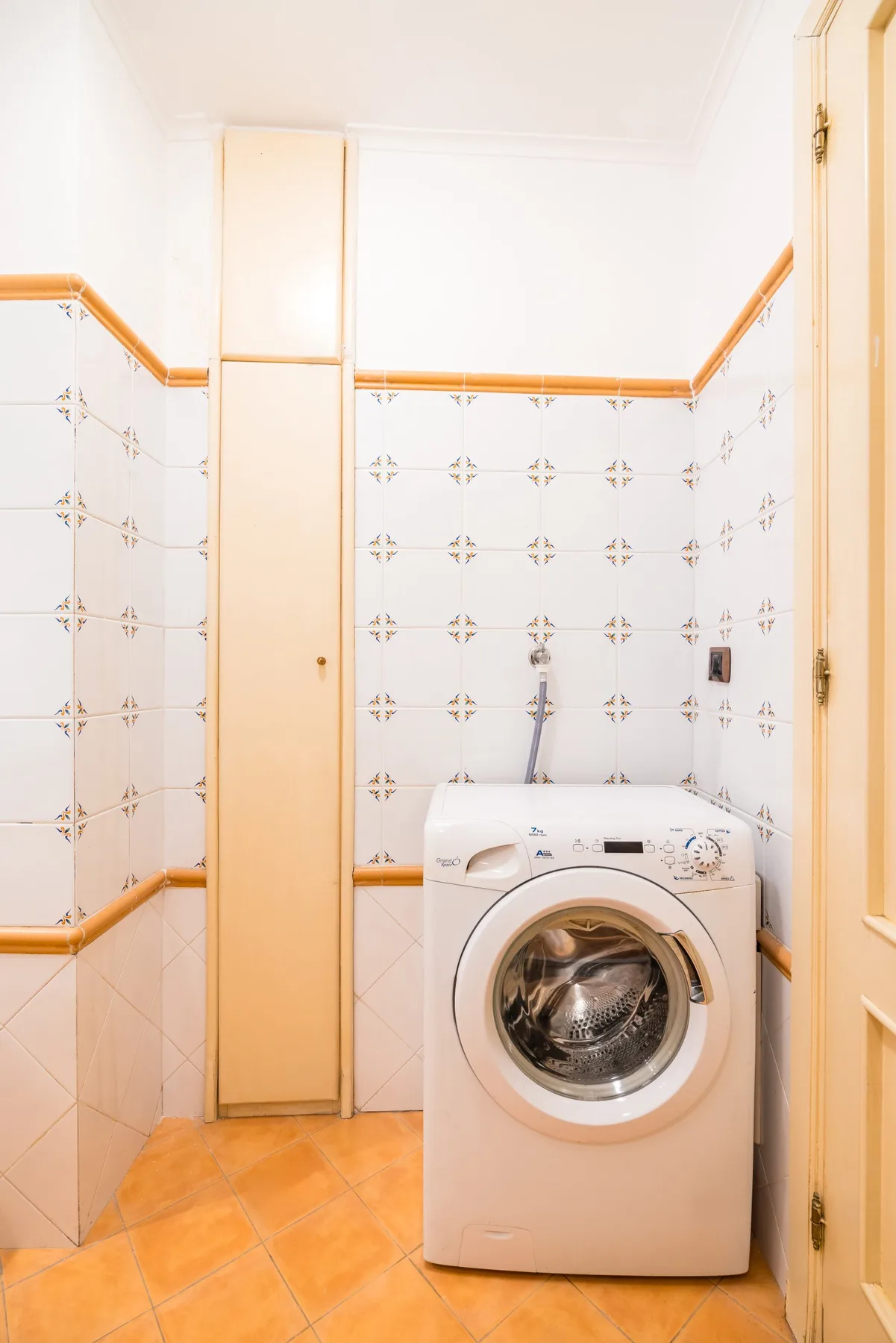 A laundry area with a front-loading washing machine beside a tall cabinet.