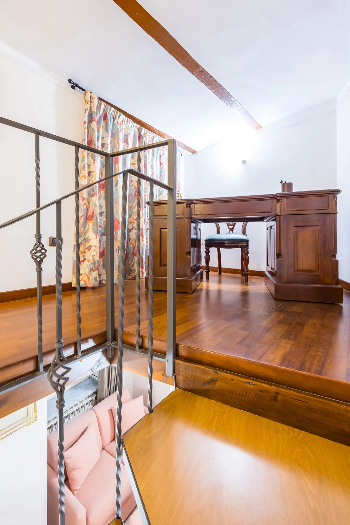 A raised wooden desk area overlooks a lower space beside a metal railing.