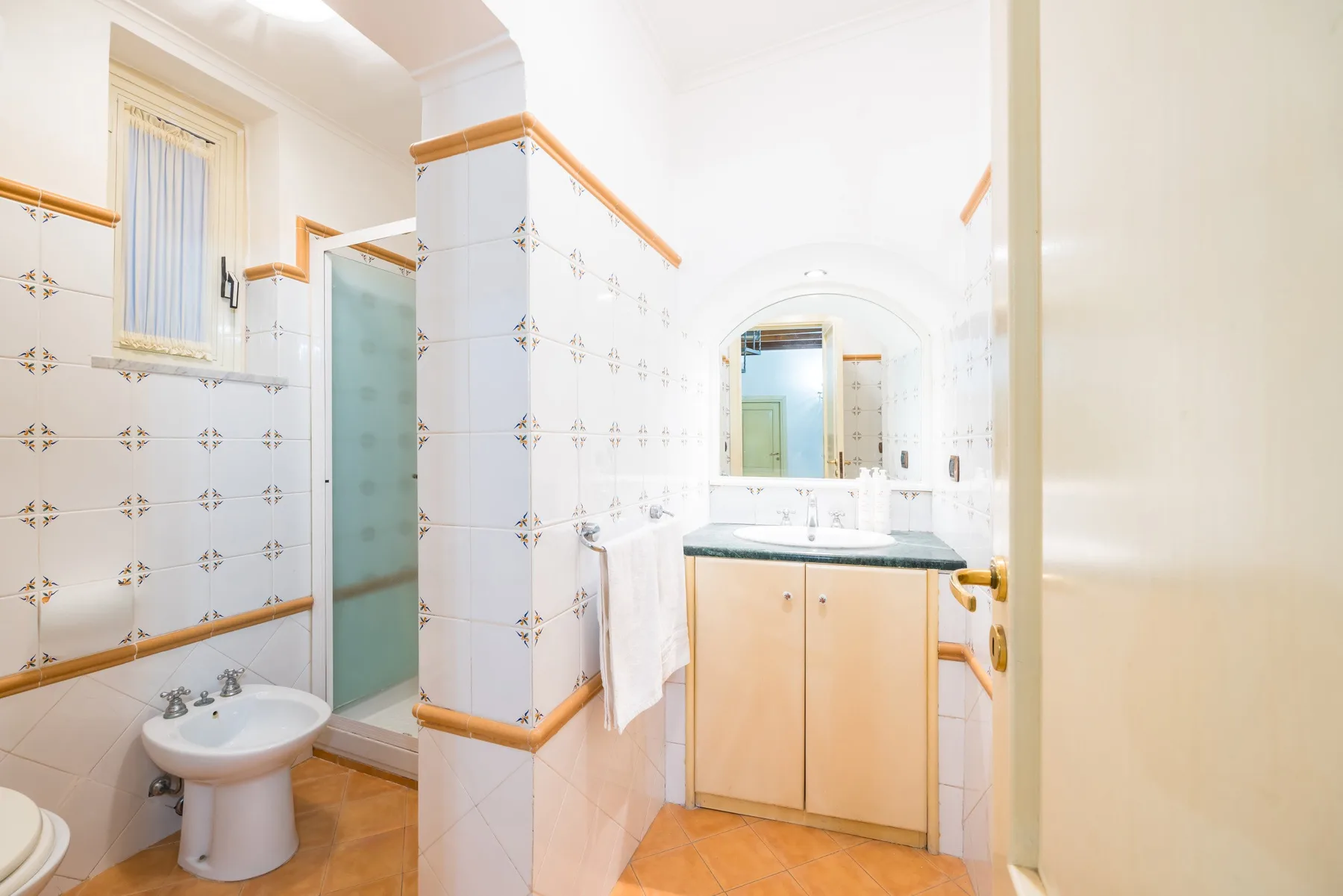 A tiled bathroom with a sink, shower, and vanity.