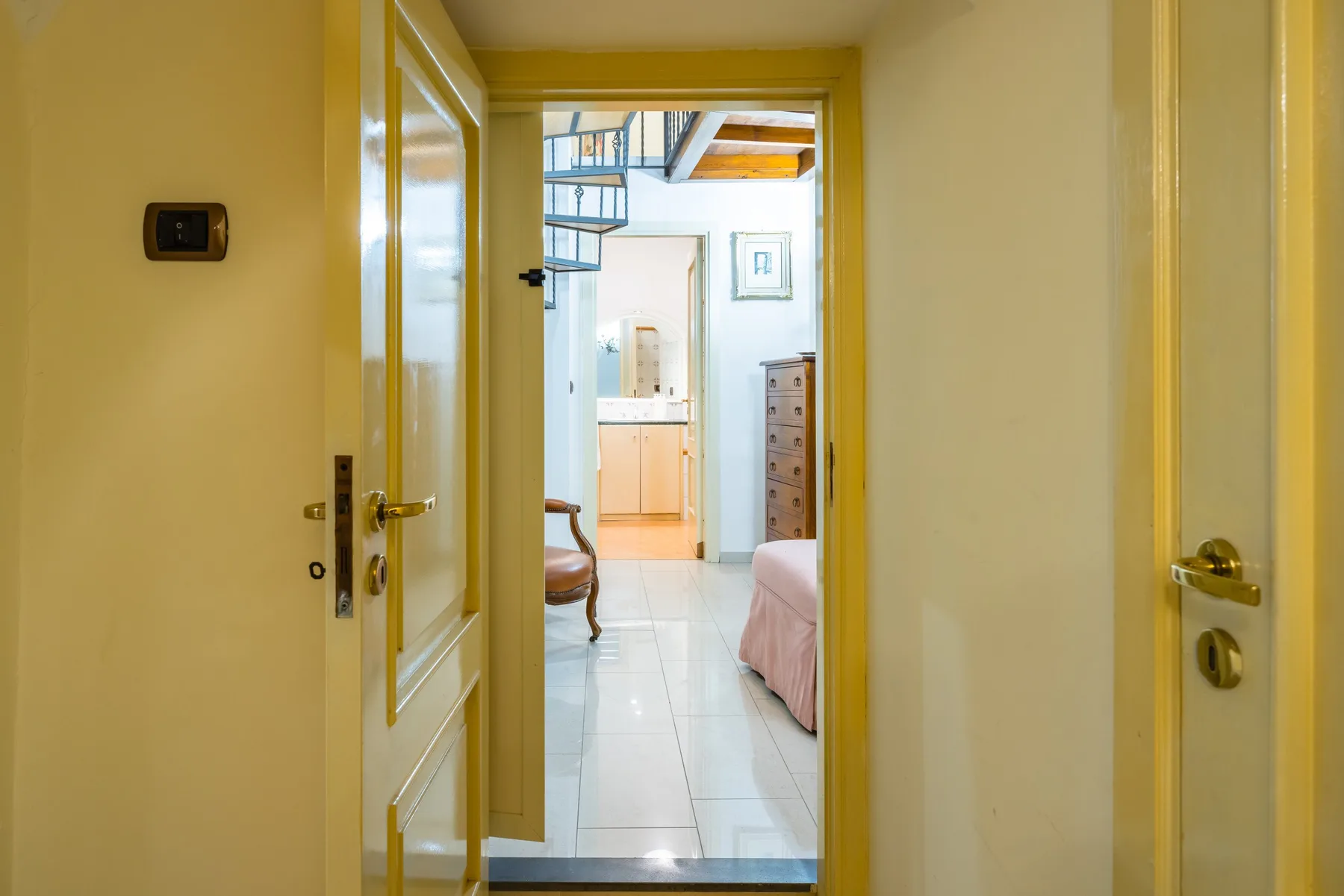 A hallway opens onto a bedroom with a bed and tiled floor.