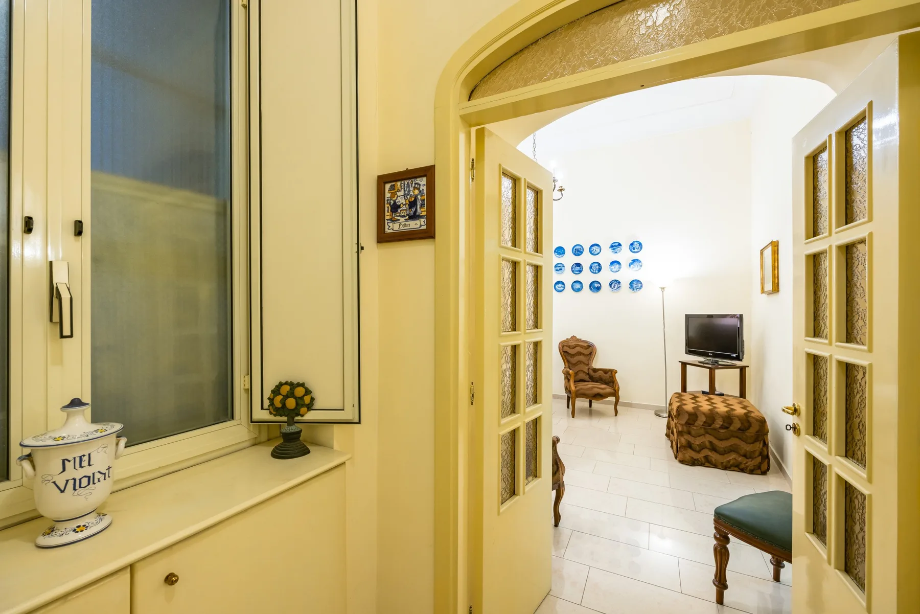 An arched doorway opens into a sitting room with a television and seating.