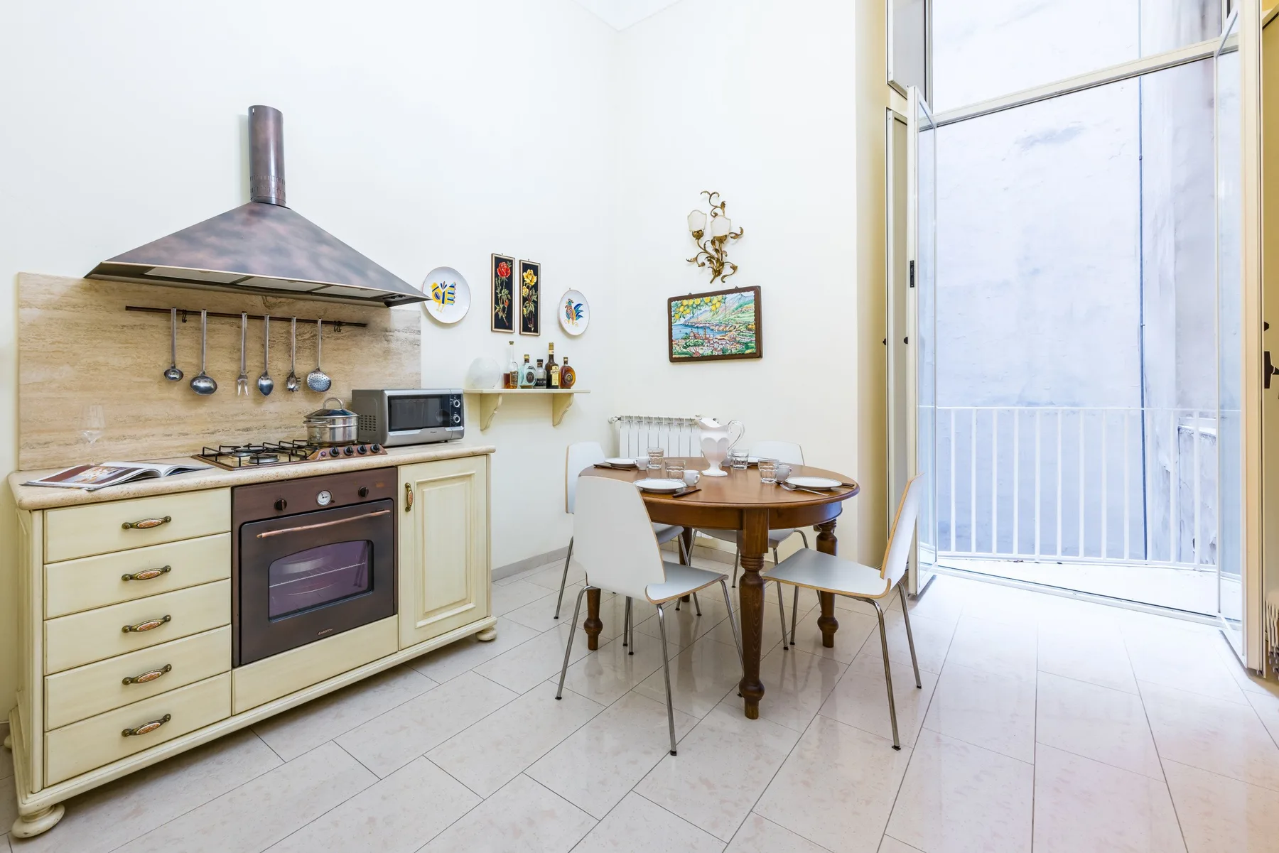 A bright kitchen and dining area with a round table beside tall glass doors.