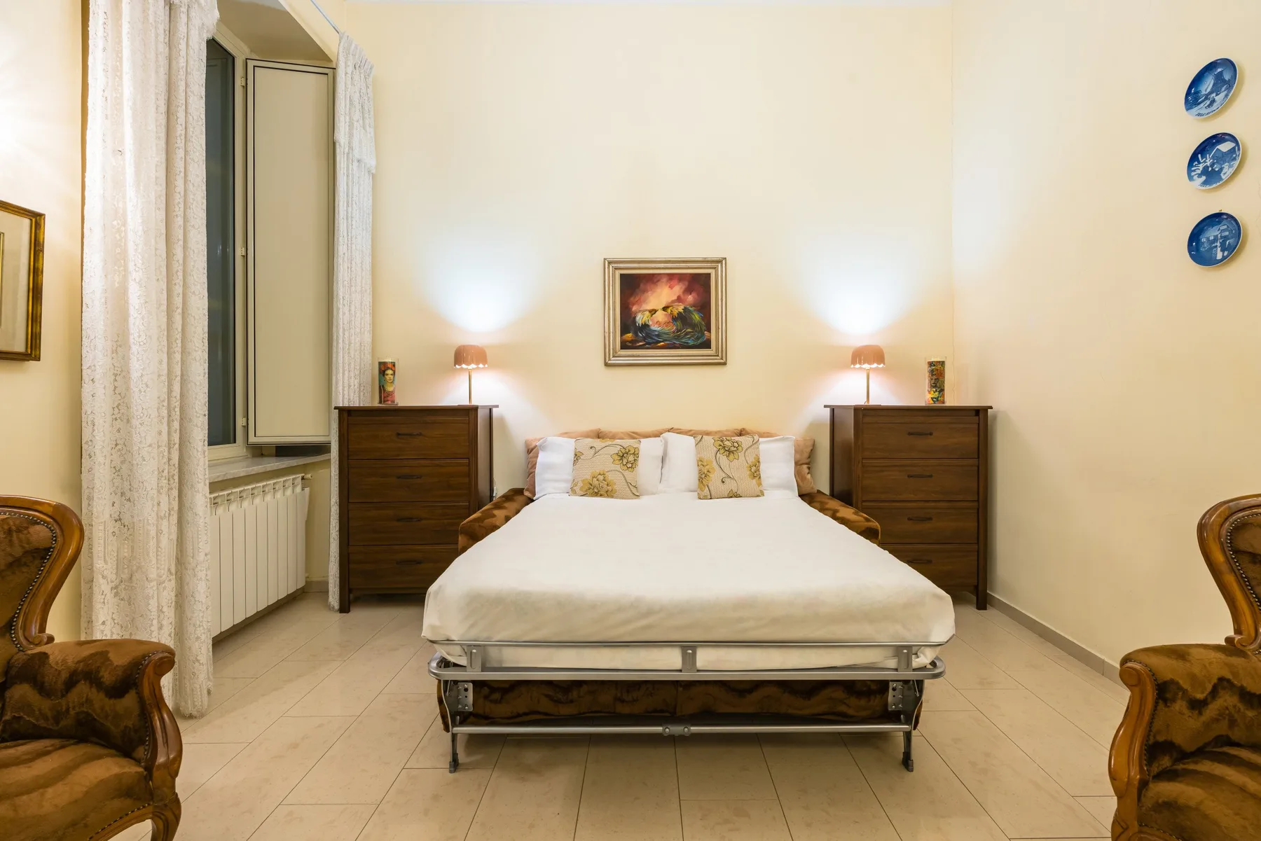 A bedroom with a bed centered between two bedside dressers.