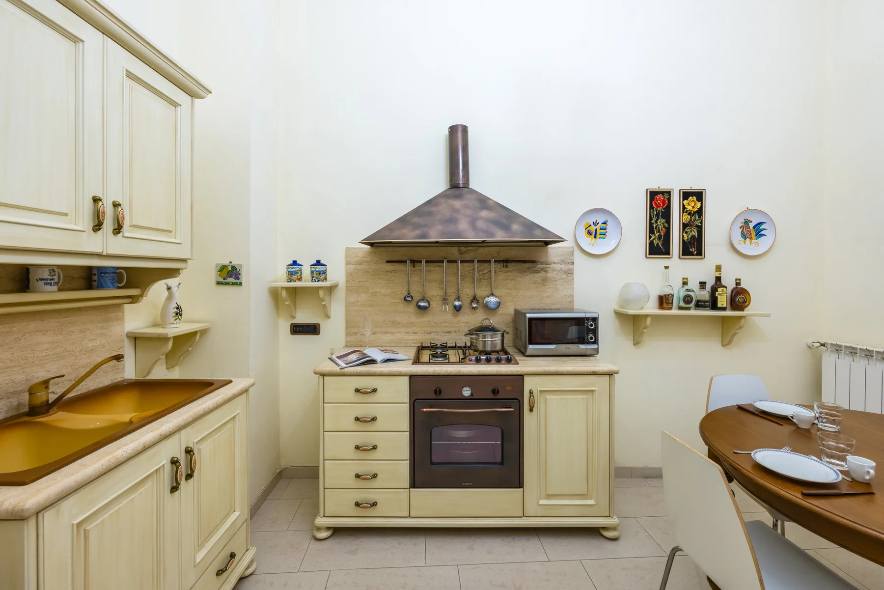 A bright kitchen with cream cabinets, a range, and a dining table.