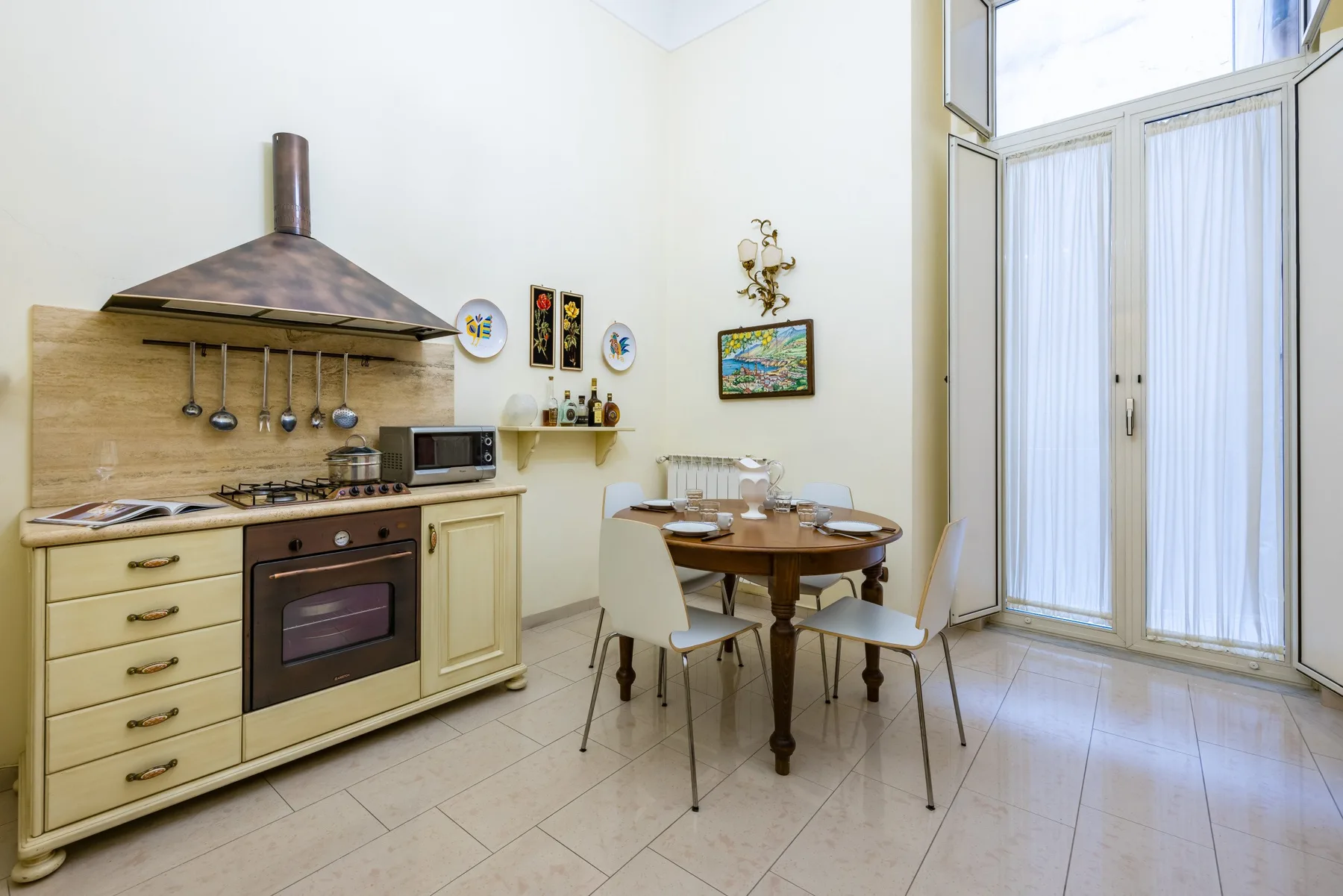 A kitchen and dining area with wooden seating beside tall glass doors.