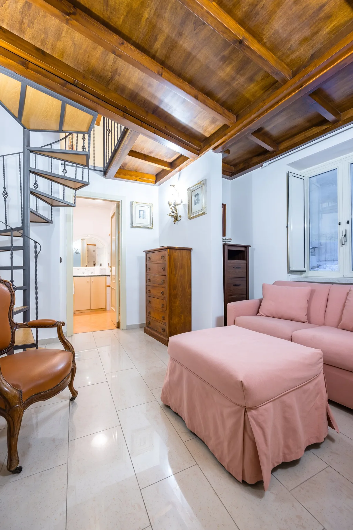 A bright living room with pink seating beneath a wooden ceiling.
